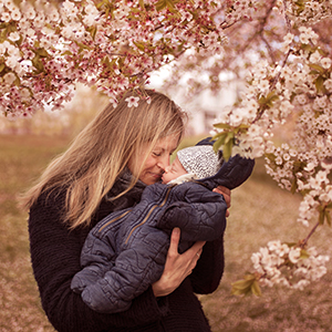 Mamma och baby fotograferade under blommande körsbärsträd i Nacka